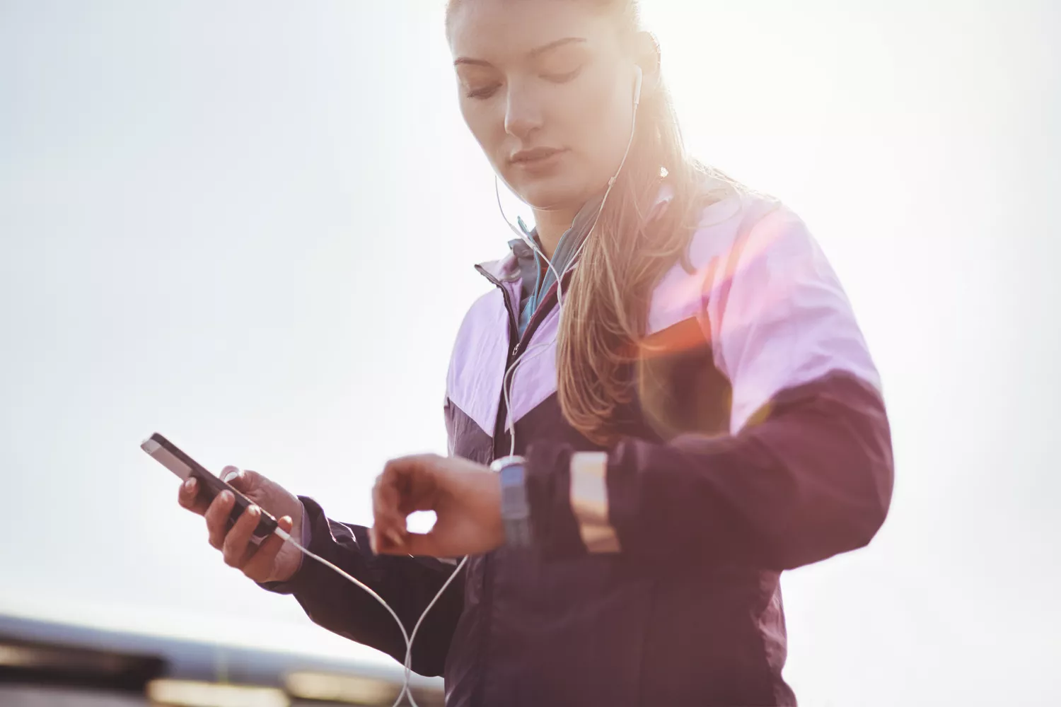 Runner wearing earphones checking time on smartwatch
